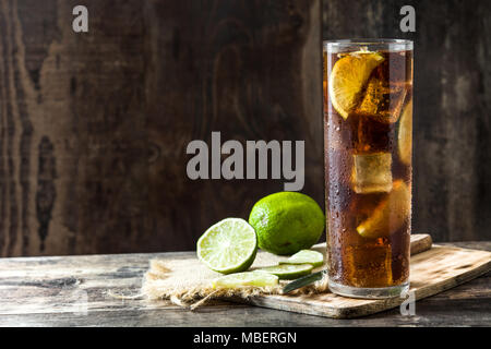 Cuba libre. Cocktail au rhum, citron vert et de la glace sur une table en bois. Banque D'Images