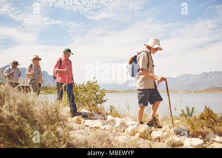 Senior les amis de la randonnée le long du lac d'été ensoleillé Banque D'Images