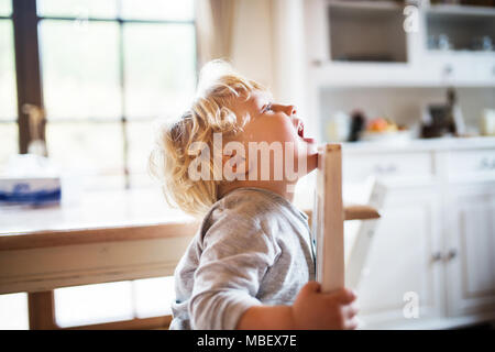 Un bébé garçon assis à la table à la maison. Banque D'Images