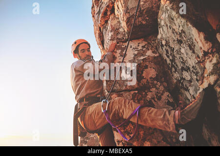 L'accent male rock climber hanging from rock Banque D'Images