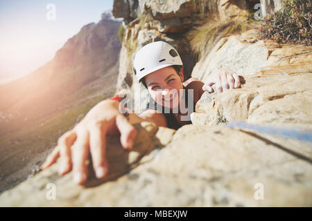 Portrait souriant, confiant rock climber reaching for rock Banque D'Images