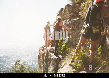 Grimpeurs escalade rochers au-dessus de l'océan ensoleillé Banque D'Images