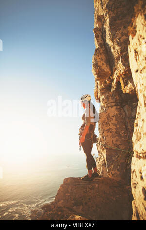 Female rock climber à ensoleillée à ocean view Banque D'Images