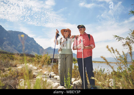 Senior couple hiking avec pôles de randonnée au lac d'été ensoleillé Banque D'Images