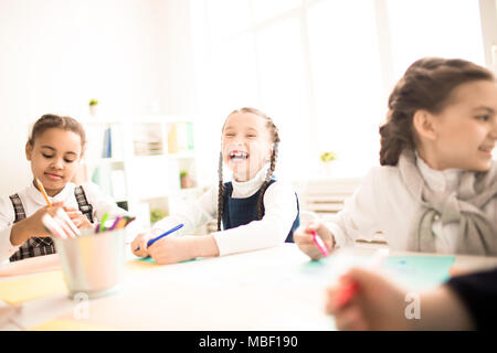 Happy girl assis à la table et rire parmi ses camarades Banque D'Images