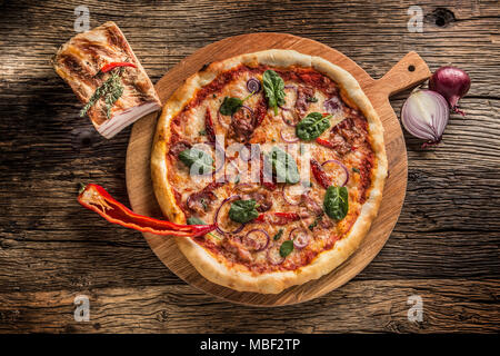 Haut de la pizza italienne panorama avec chili bacon oignon et le basilic sur plaque de bois rond et de sélection. Banque D'Images