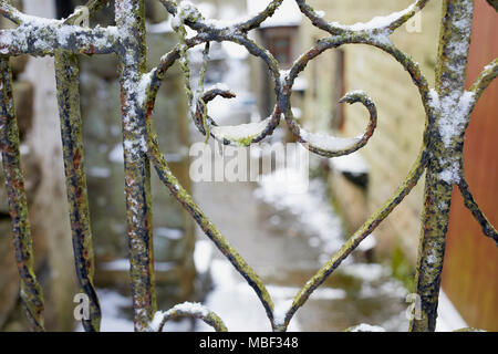 La neige et la glace reste sur la rouille en forme de coeur porte en fer forgé. Nidderdale. Banque D'Images