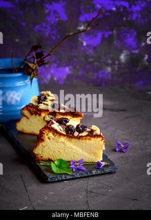 Deux morceaux de gâteau au fromage au chocolat coulé et décorées avec des petits fruits cerise séchée sur un fond noir Banque D'Images