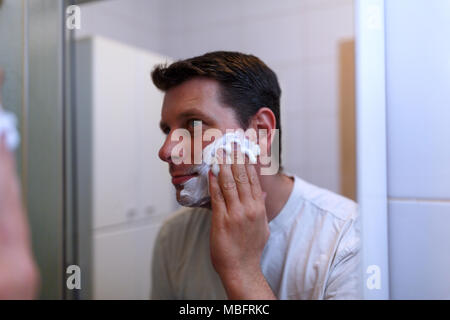 Happy handsome man shaving in bathroom Banque D'Images