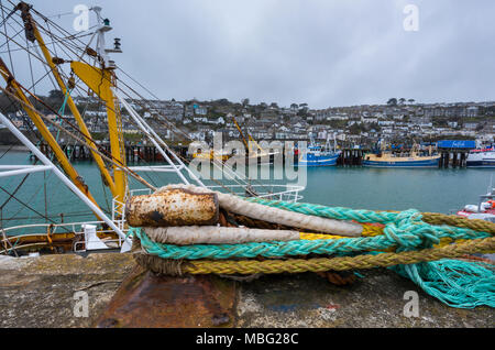 Des cordes attachées à un point fixe sur le mur du port de Newlyn à Cornwall. Les bateaux de pêche amarrés à quai et le long du mur dans un Cornish principal port de pêche. Banque D'Images