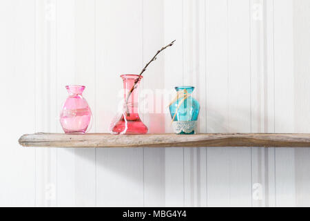 Trois vases en verre de couleur pastel avec des chatons sont sur le vieux bois Banque D'Images