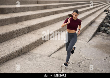 Jeune femme sportive d'exécution sur l'escalier des vêtements fitness avec cheveux attachés en arrière