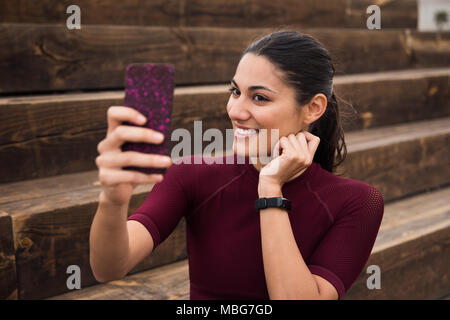 Belle brune prendre une photo d'elle-même portait un shirt de sport marron, Black Watch et les cheveux attachés en arrière Banque D'Images