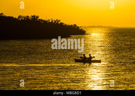 USA, Floride, coucher du soleil orange intense lumière avec petit canot dans l'eau Banque D'Images