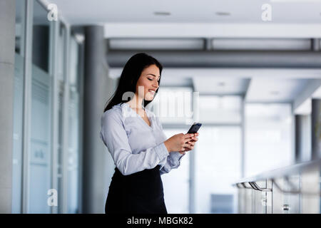 Femme à appeler quelqu'un bâtiment d'affaires avec téléphone Banque D'Images