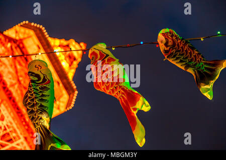 Tokyo, Japon - 23 Avril 2017 : détails d'une carpe Koinobori vent en forme d'avion traditionnellement chaussettes au Japon pour célébrer la Journée de l'enfance. La Tour de Tokyo par nuit brouillée sur arrière-plan. Plan horizontal. Banque D'Images