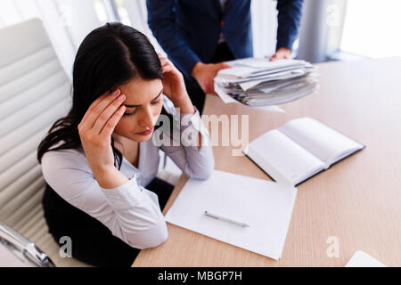 Businesswoman having maux de tête d'avoir trop de travail à faire à partir de son patron Banque D'Images