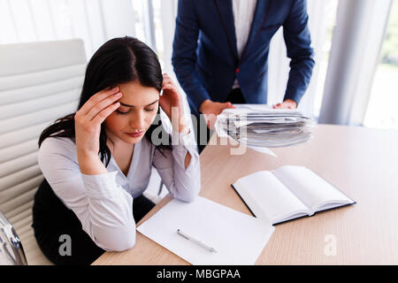 Businesswoman having maux de tête d'avoir trop de travail à faire à partir de son patron Banque D'Images