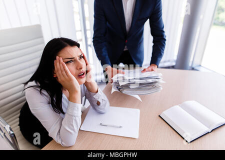 Businesswoman having maux de tête d'avoir trop de travail à faire à partir de son patron Banque D'Images