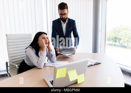 Businesswoman having maux de tête d'avoir trop de travail à faire à partir de son patron Banque D'Images