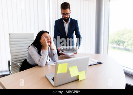 Businesswoman having maux de tête d'avoir trop de travail à faire à partir de son patron Banque D'Images