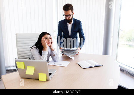 Businesswoman having maux de tête d'avoir trop de travail à faire à partir de son patron Banque D'Images