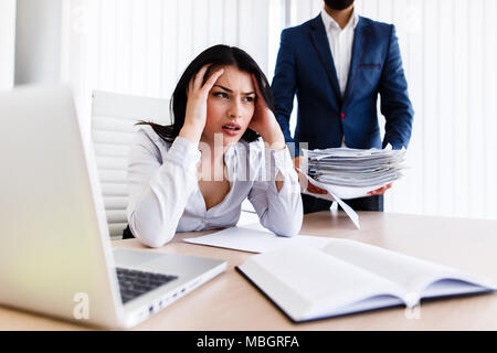 Businesswoman having maux de tête d'avoir trop de travail à faire à partir de son patron Banque D'Images