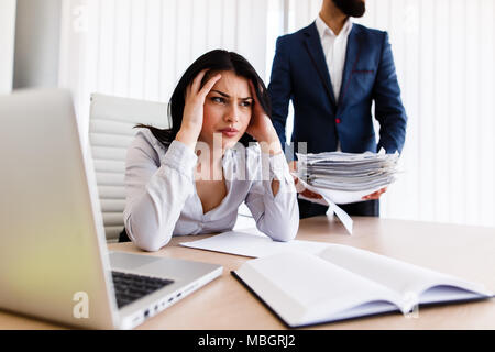 Businesswoman having maux de tête d'avoir trop de travail à faire à partir de son patron Banque D'Images