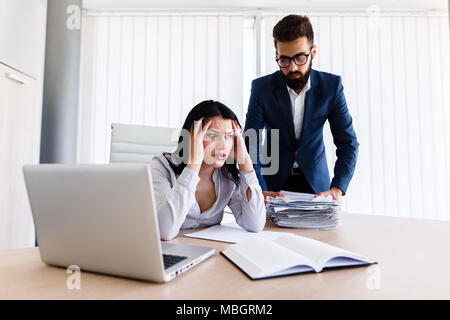 Businesswoman having maux de tête d'avoir trop de travail à faire à partir de son patron Banque D'Images