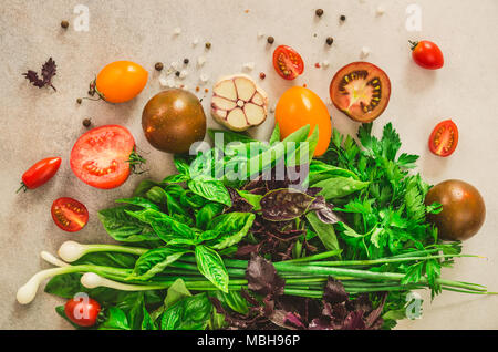 Épinards frais, l'oignon vert, le basilic, les herbes, les tomates et l'aneth sur fond de béton gris, selective focus. Vue d'en haut. Effet tonique. Ingrédients de cuisson des aliments. Végétalienne, crue, concept detox Banque D'Images