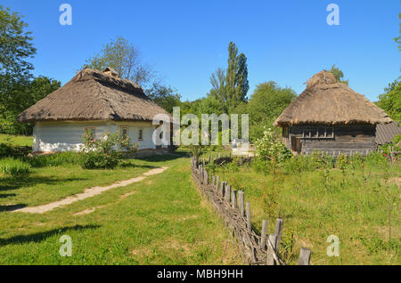 Deux anciennes maisons vintage : argile et en bois. Entouré d'herbe, les arbres et une clôture en bois Banque D'Images