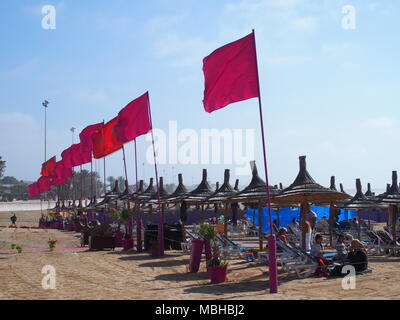 AGADIR, Maroc afrique sur février 2017 : Rouge drapeaux marocains et des parasols sur la plage paysages en ville voyage avec ciel bleu clair en hiver ensoleillé chaud Banque D'Images