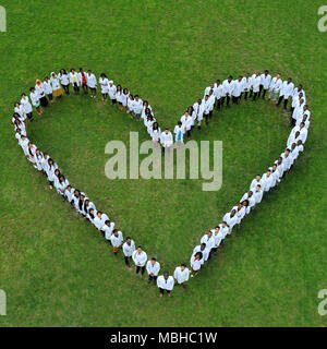 Kiev, Ukraine - 22 Avril 2018 : de jeunes étudiants en médecine debout sur le sol, faisant de grands vivre la charité coeur . Les personnes de nationalités différentes. Physycians vêtus de blanc uniforme médical. Banque D'Images