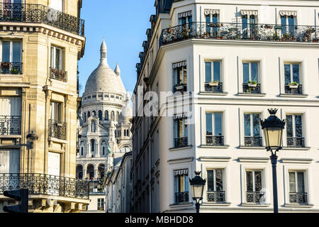 La basilique du Sacré-Cœur à Paris grâce à une rue étroite entre les bâtiments typiques avec vintage des lumières de rue au premier plan. Banque D'Images