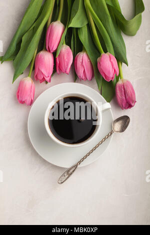 Tasse de café noir en blanc avec des tulipes roses sur fond noir en lumière. Top View with copy space Banque D'Images