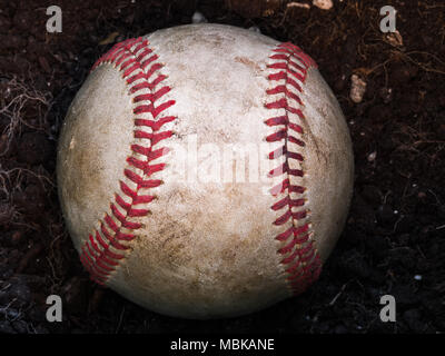 Close up sports image d'arrière-plan d'une vieille en cuir patiné baseball portant sur un tas de poussière brun montrant le détail complexe et lacets rouges. Banque D'Images