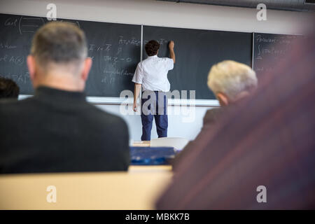 Senior male teacher teaching mathematics, écrit sur le tableau noir Banque D'Images
