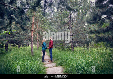 Jeune couple hipster en chemise à carreaux se tenant par la main dans la pinède. L'amour dans la nature. Banque D'Images