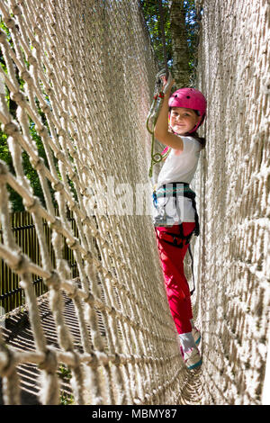 Jeune fille dans le faisceau de l'escalade et d'essayer dans un parc aventure. Banque D'Images