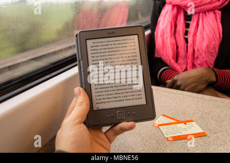 La lecture d'un Kindle sur un voyage en train, avec des billets de train sur la table et d'une personne d'en face Banque D'Images