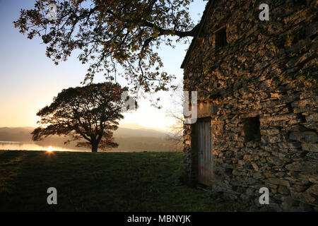 Coucher de soleil sur le lac Windermere allume le mur de pierres sèches d'un bâtiment agricole dans le Lake District, Cumbria, Royaume-Uni. Banque D'Images