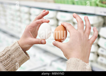 Mains d'une femme avec le blanc et le brun oeufs dans le magasin Banque D'Images