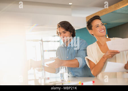 Smiling business people brainstorming, passant dans la salle de réunion de la paperasserie Banque D'Images