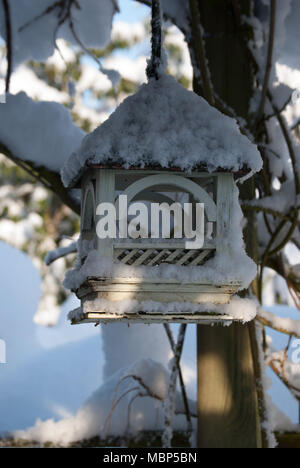 Oiseaux en bois peint le tableau accroché sur un arbre couvert de neige. Image d'hiver. Banque D'Images