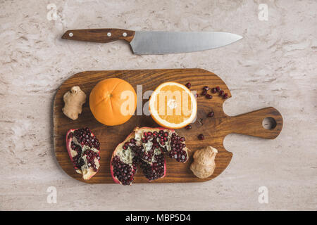 Vue de dessus d'oranges, la grenade et le gingembre on cutting board Banque D'Images