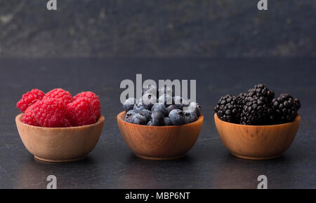 Fruits des bois, framboises, bleuets et mûres, sur une planche à découper ardoise Banque D'Images