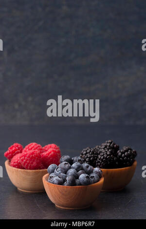 Fruits des bois, framboises, bleuets et mûres, sur une planche à découper ardoise Banque D'Images