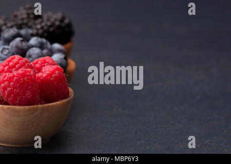 Fruits des bois, framboises, bleuets et mûres, sur une planche à découper ardoise Banque D'Images