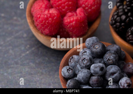 Fruits des bois, framboises, bleuets et mûres, sur une planche à découper ardoise Banque D'Images