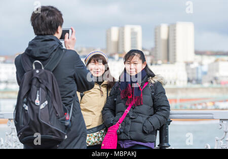 Les touristes japonais ayant photo prise à la station balnéaire de Brighton, East Sussex, Angleterre, Royaume-Uni. Banque D'Images